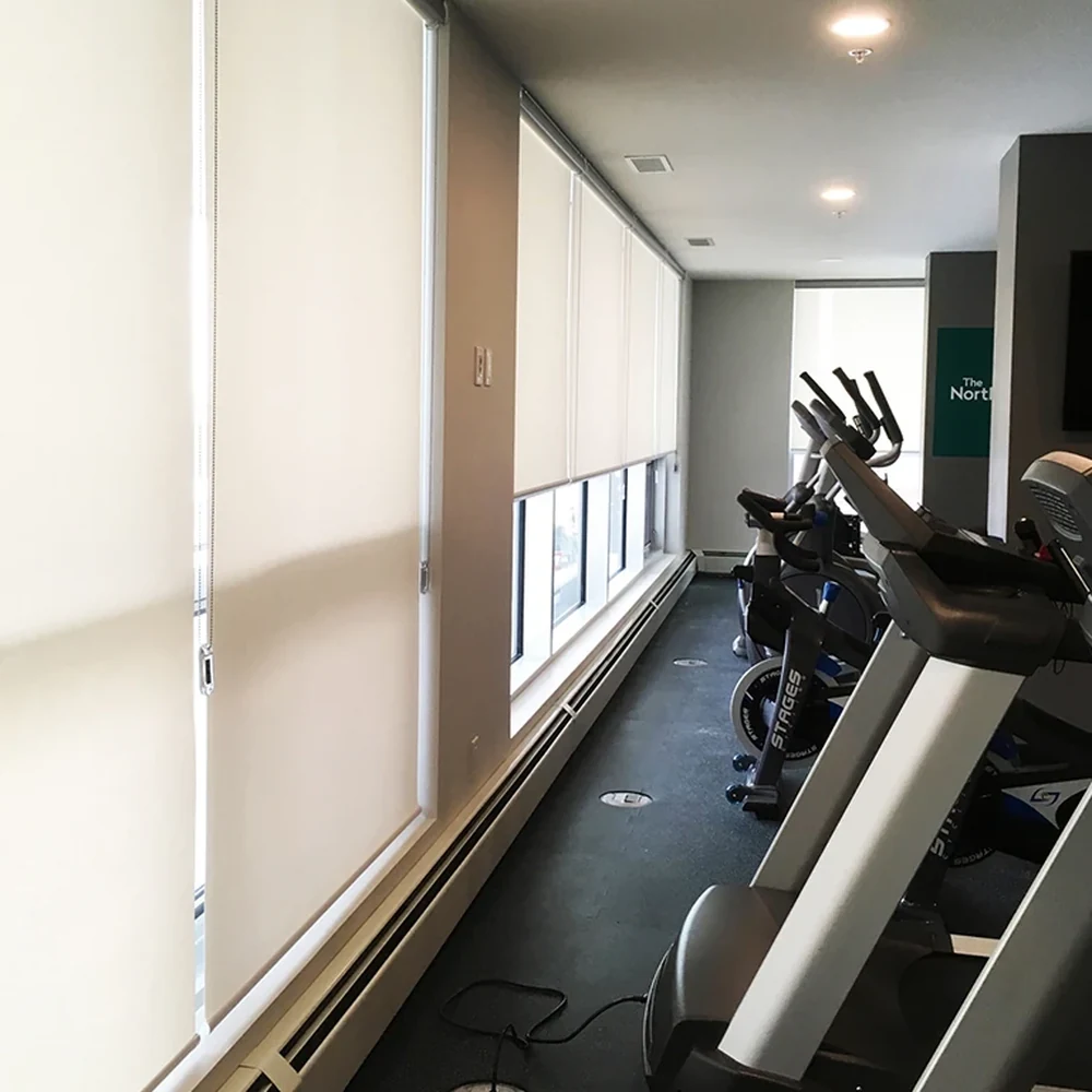 Roller shades fitted along windows in a fitness space